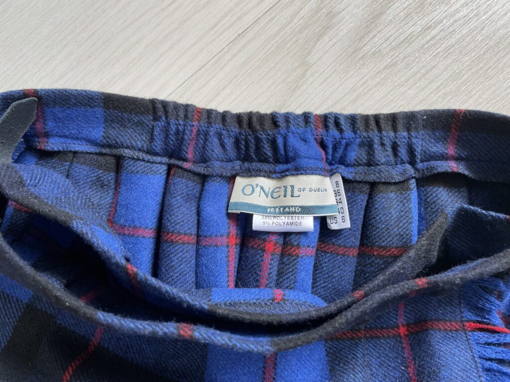オニールオブダブリンのスカートの、ウエスト内側に付いているタグの画像。ブランドロゴ・サイズ・洗濯表示の3つのタグが付いている。