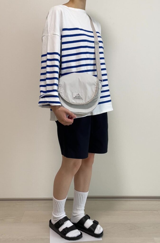 女性がボーダートップスとハーフパンツを着て、白いソックスの上からアリゾナEVAを履いている。