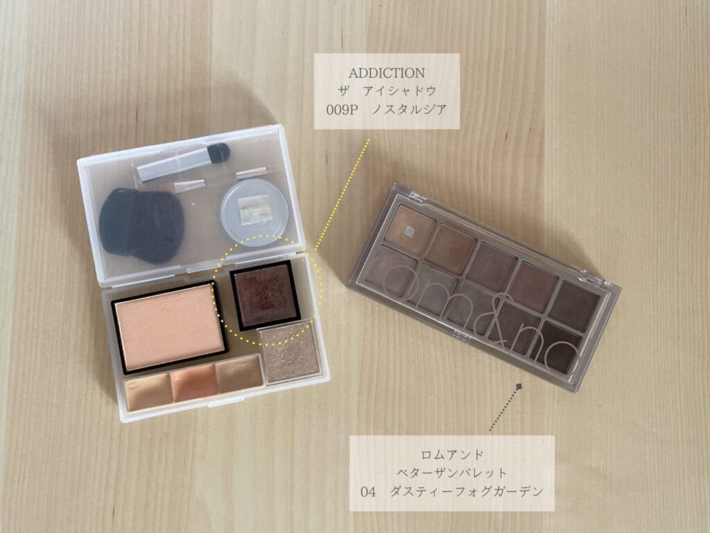 手作りしたメイクパレットと、ロムアンドのべターザンパレットが並べて置いてある。手作りパレットの中にアディクションのザアイシャドウのノスタルジアがあることが文字で説明してある。ロムアンドのパレットの色はダスティーフォグガーデンであると表記してある。