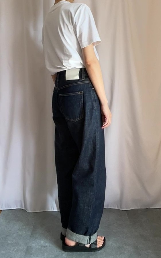 白いTシャツに濃紺デニムを履いている。
