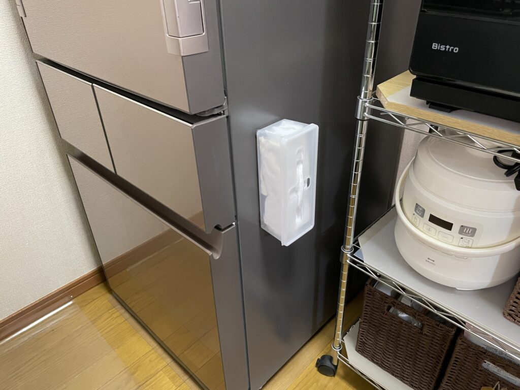キャンドゥの収納ケースに使い捨てクロスを入れ、冷蔵庫の横に貼り付けてある。