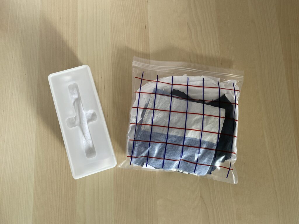ジッパー付きポリ袋と、キャンドゥの収納ケースのそれぞれに、手のひらサイズにカットされた布が入っている。