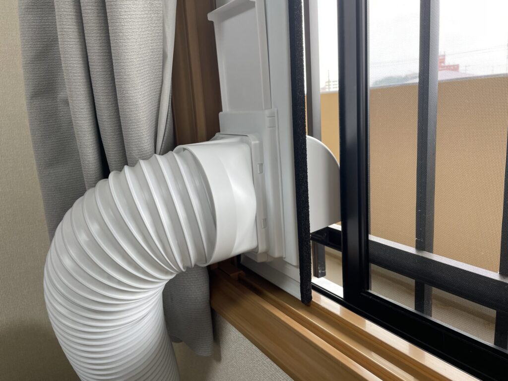 二重窓にスポットクーラーの窓パネルを取り付けてある。これにより、網戸を完全に閉められない状態になっている。